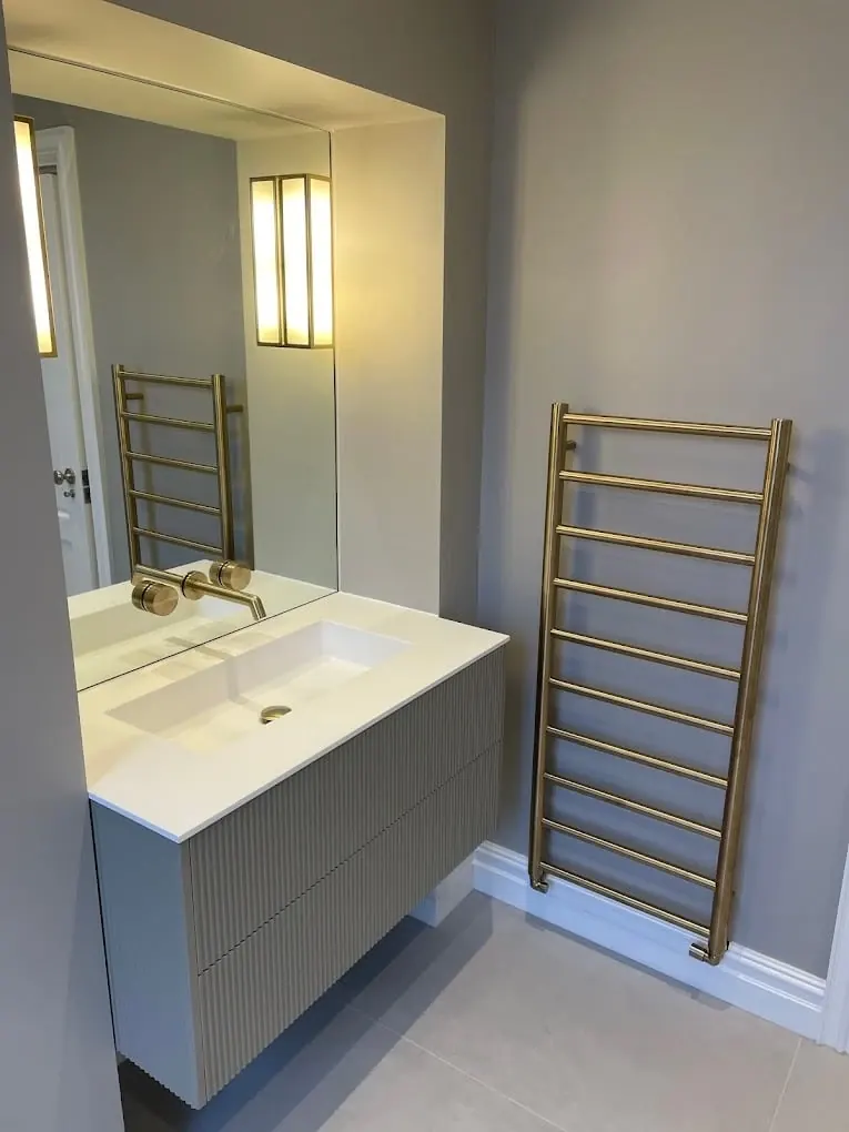Brushed brass heated towel rail and floating vanity with backlit mirror