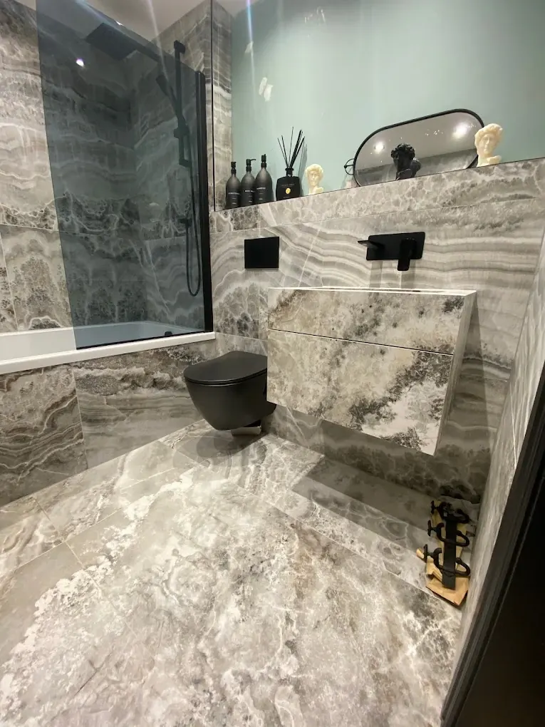 Stone-tiled bathroom with floating stone basin, black wall-mounted taps and black wall-hung toilet