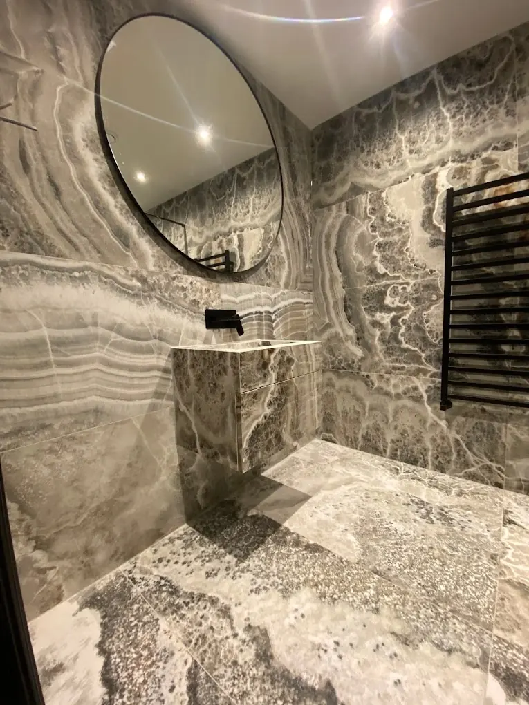 Round black-framed mirror over stone basin plinth with black towel radiator