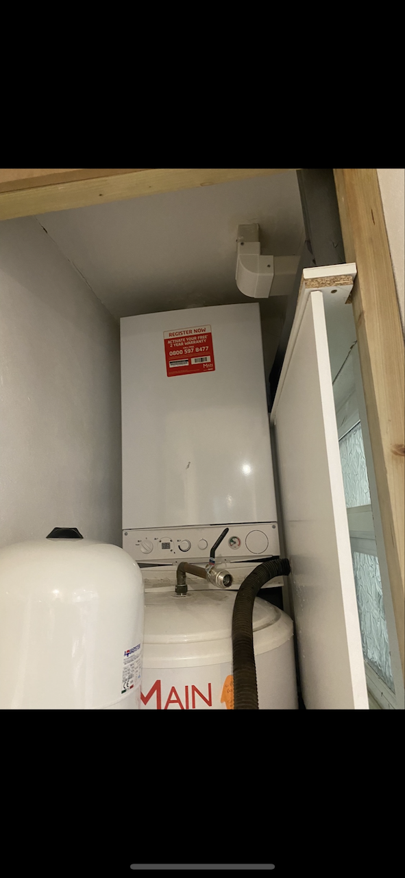 Old Main system boiler sat on top of unvented cylinder in cupboard