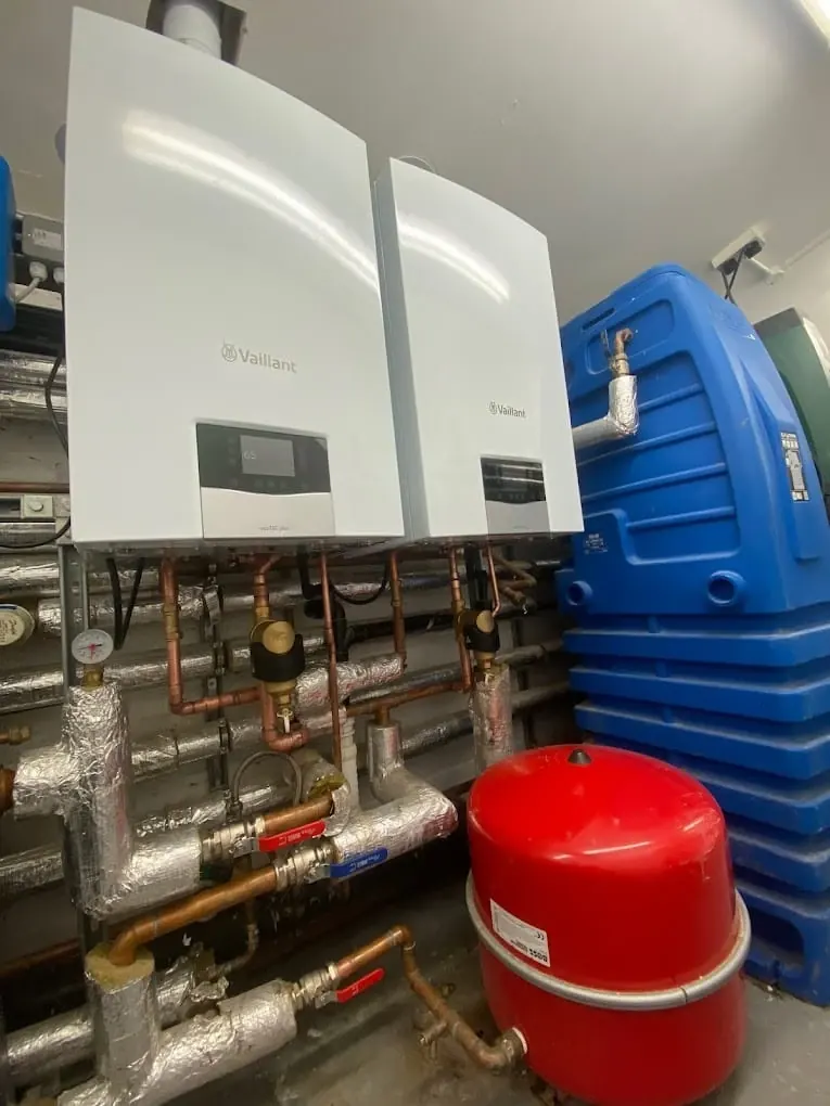 Commercial plant room with twin Vaillant wall-hung boilers, insulated pipework and red expansion vessel