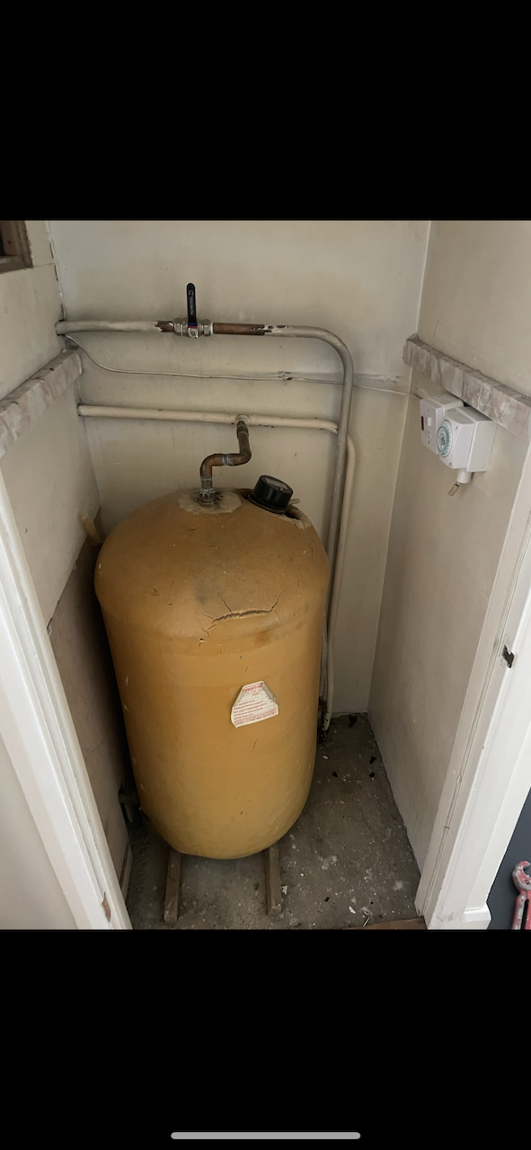 Old vented cylinder in airing cupboard before removal