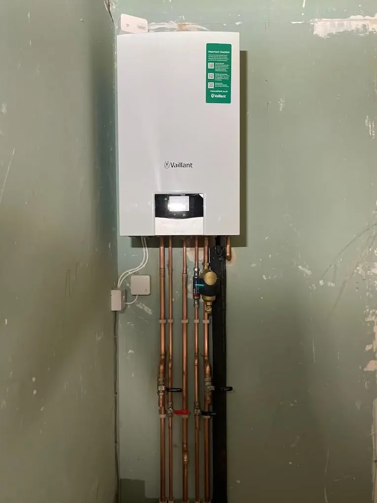 Vaillant combi boiler first fix with copper drops on stripped-back wall